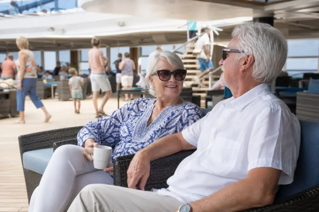 Cruise line reviews for seniors showing a relaxed couple on a busier mainstream ship